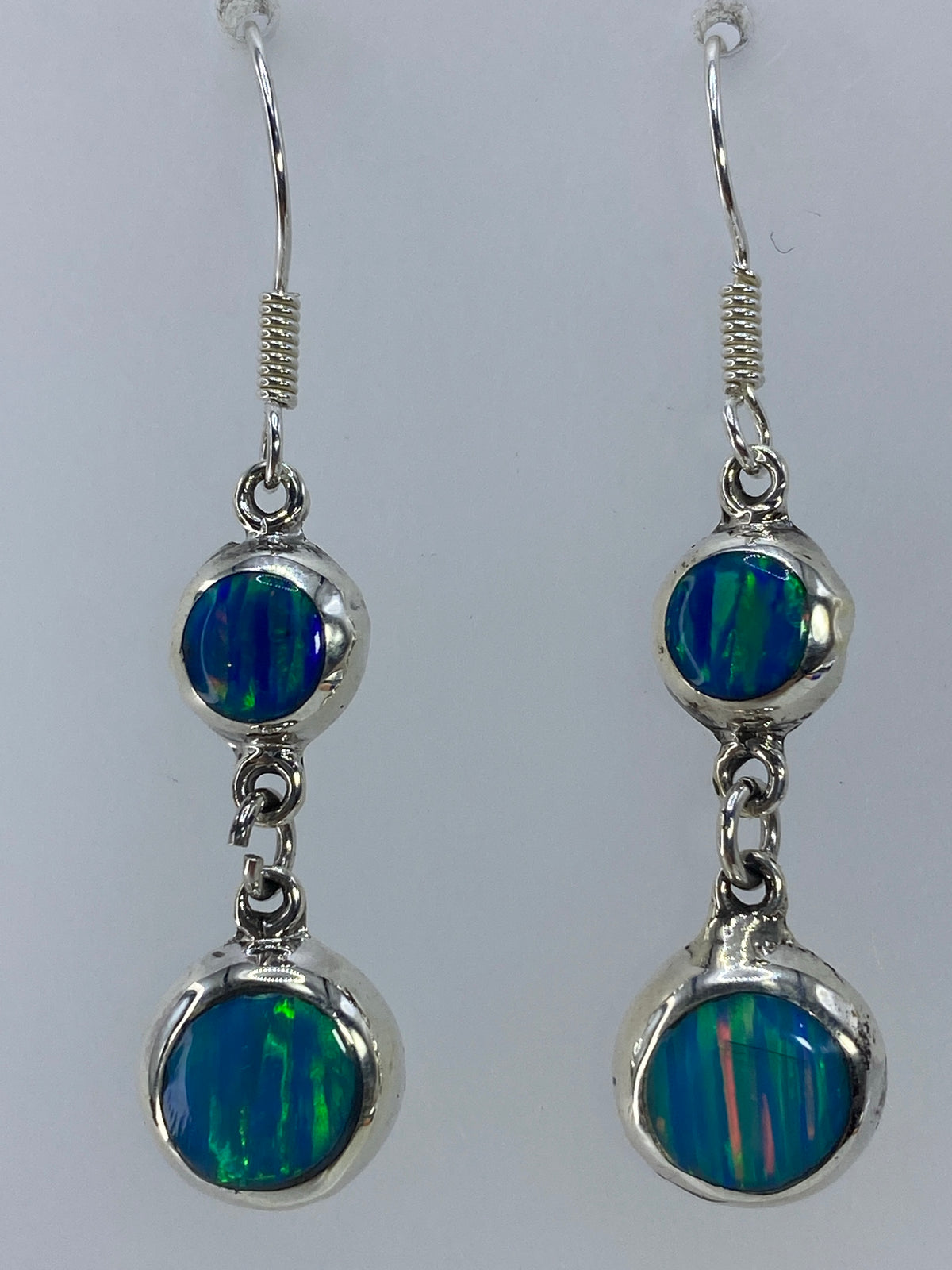 Par de aretes de plata 925 con ópalo de fuego verde olivo, colgando sobre fondo blanco