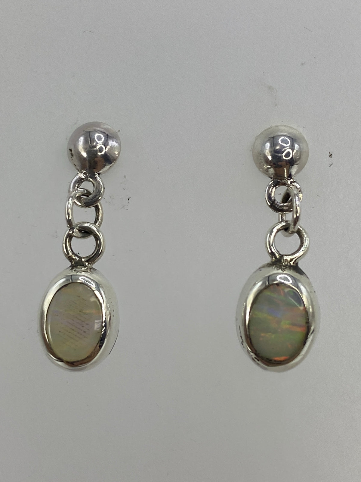 Aretes colgando mostrando los destellos cálidos del ópalo