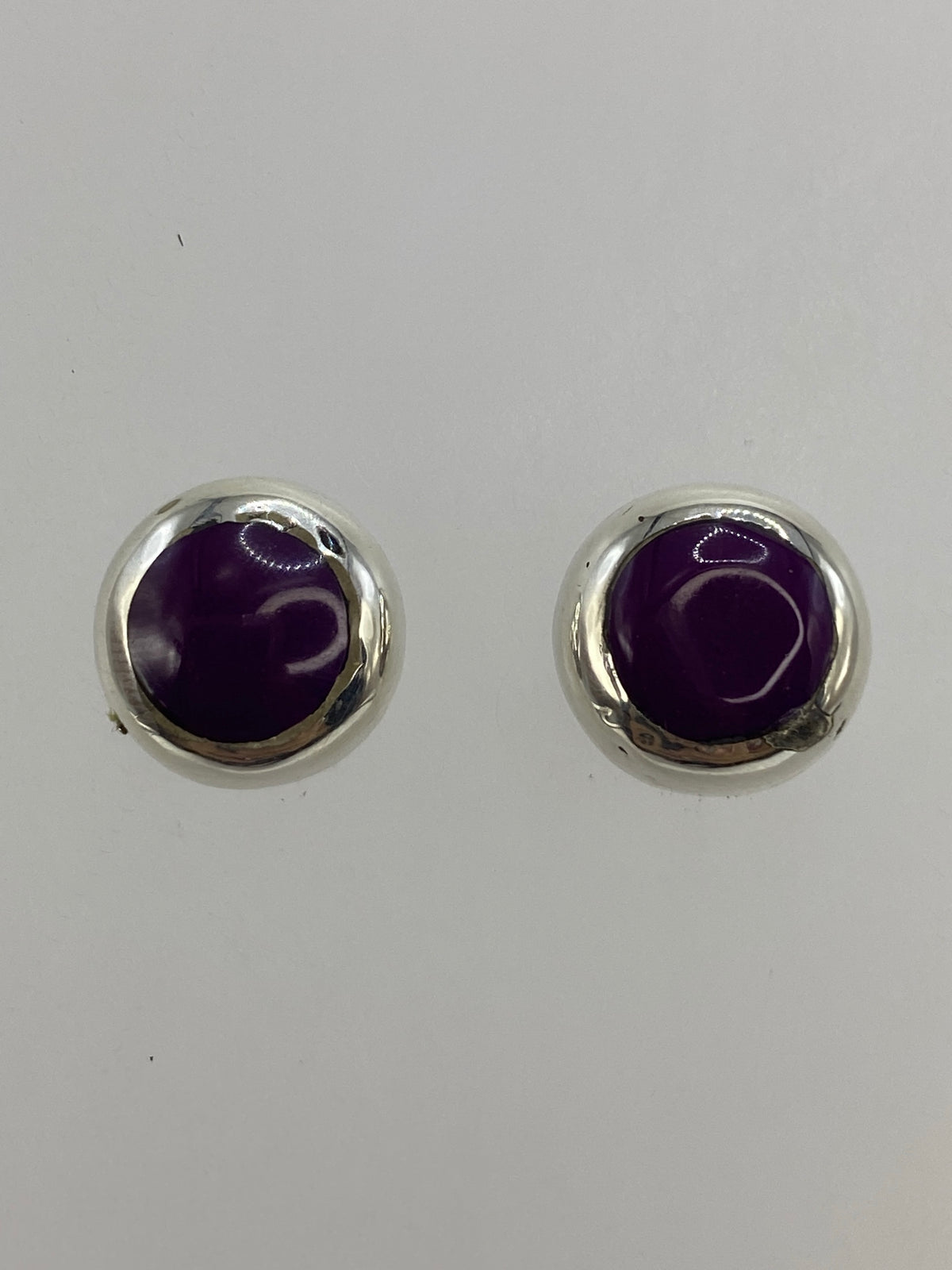 Aretes de plata con piedra morada engastada, vistos de frente