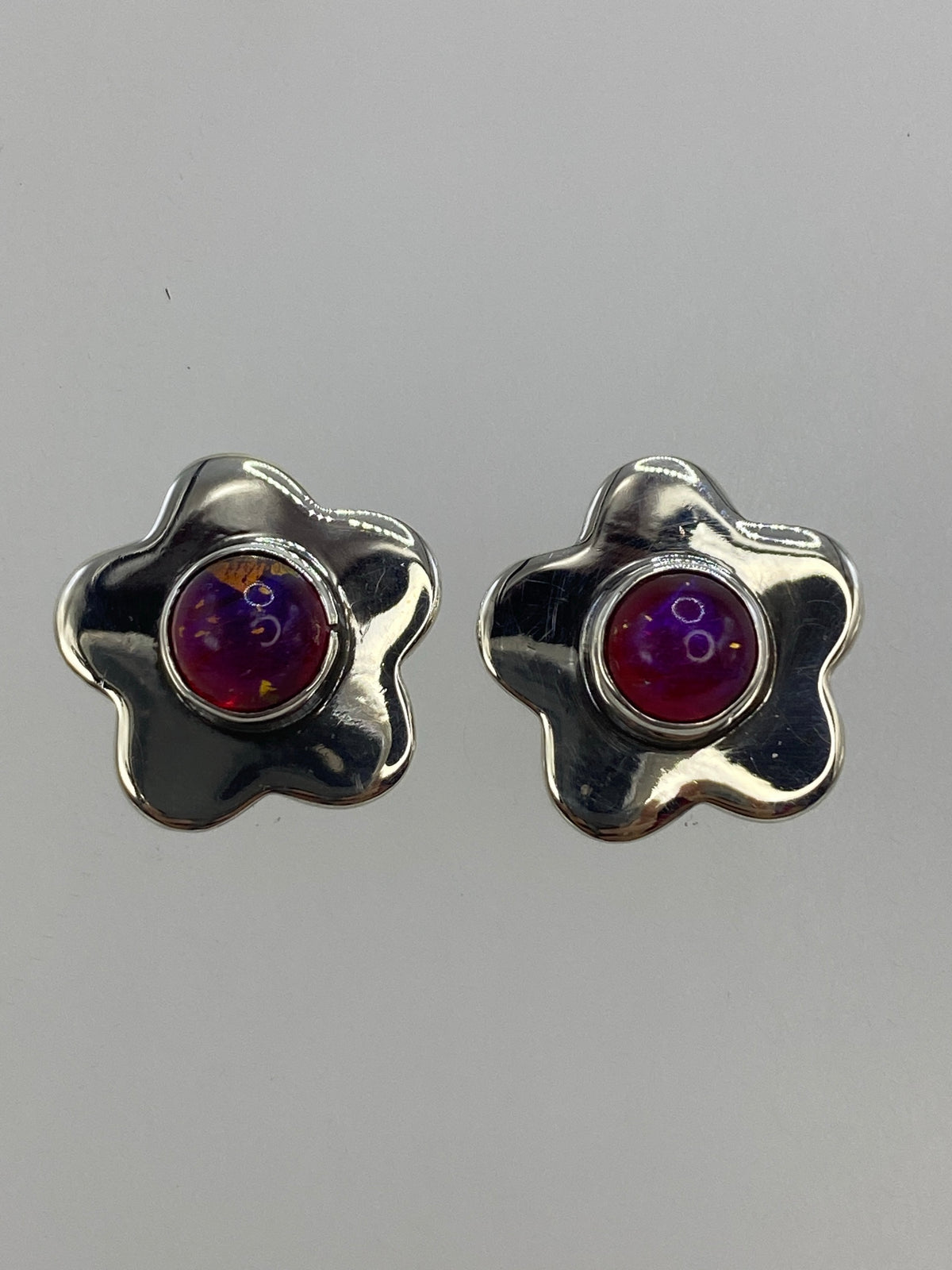 Par de aretes de plata 950 con piedra morada en forma de flores de cuatro pétalos