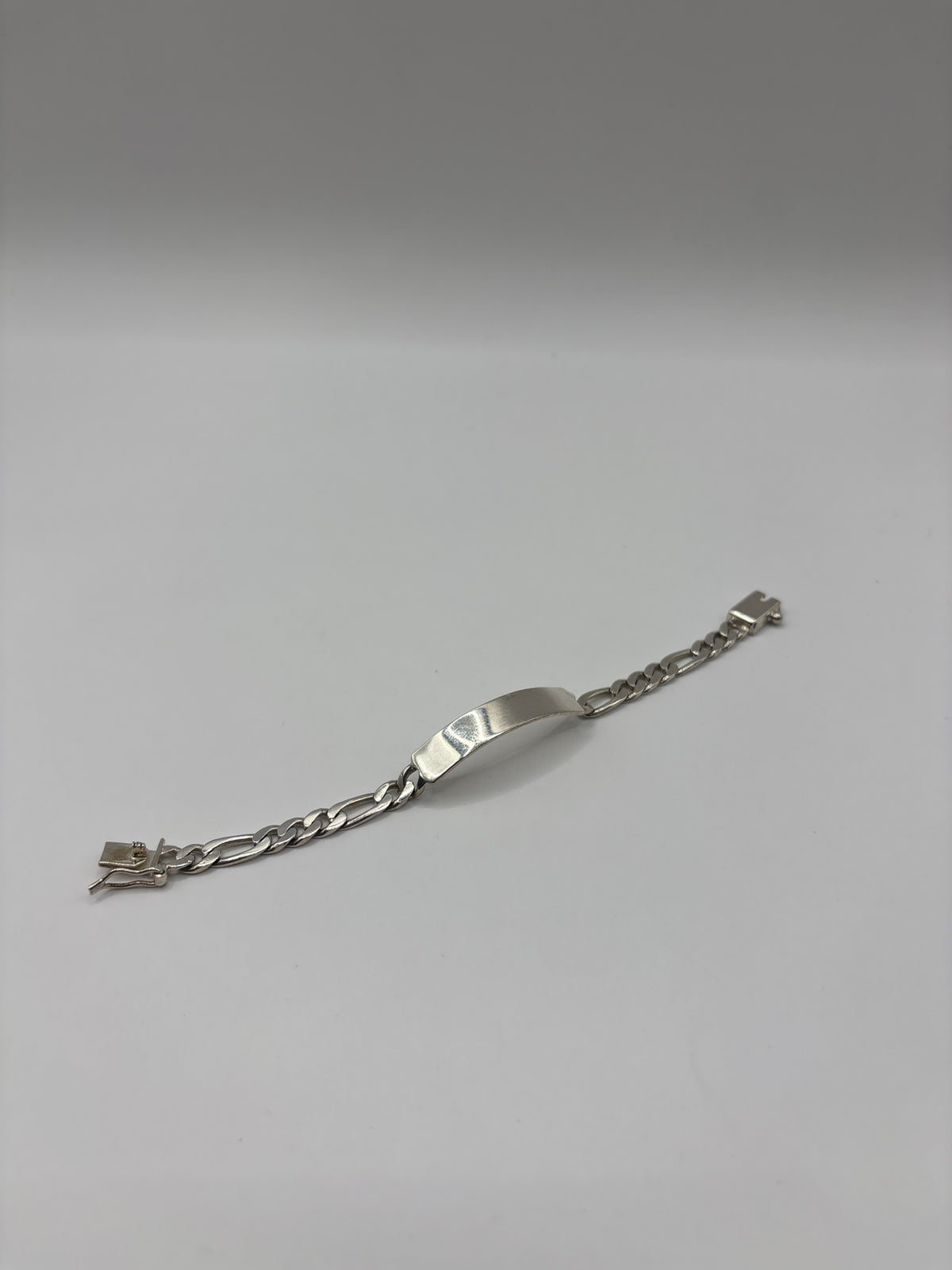 Detalle de cierre de broche de seguridad en pulsera eslabón figaro de plata pura