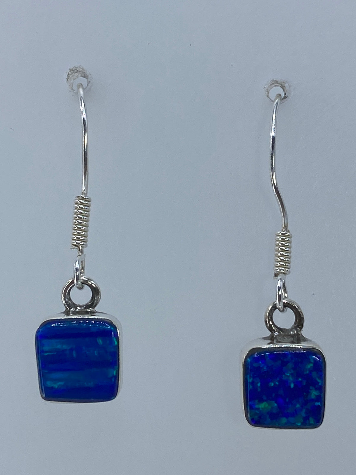 Par de aretes de plata con ópalo de fuego verde olivo colgando, vista frontal