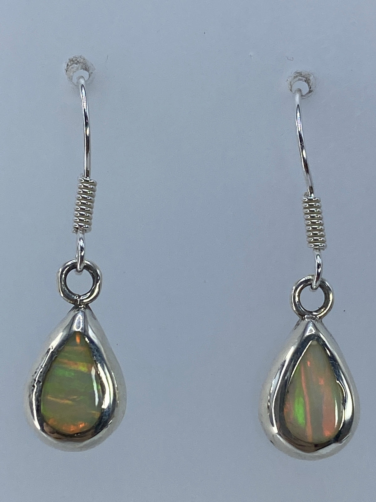 Aretes con gancho de plata mostrando los reflejos multicolor del ópalo de fuego