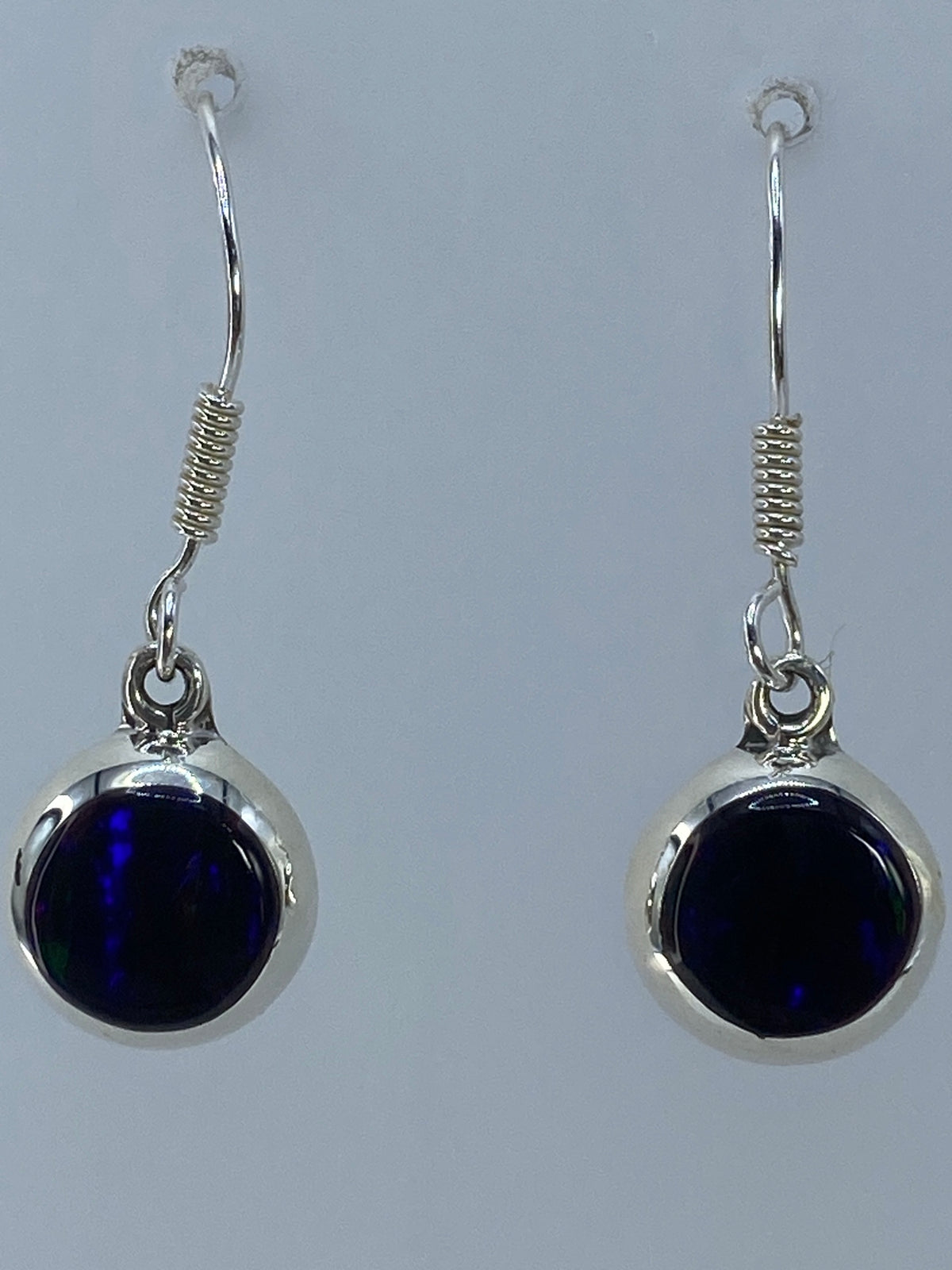 Aretes en muñeca mostrando el tamaño de 3 cm y el juego de luz del ópalo