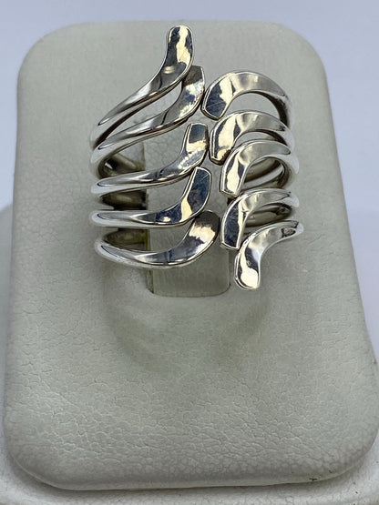 Anillo de plata repujado con eslabones arqueados en la mano de una mujer