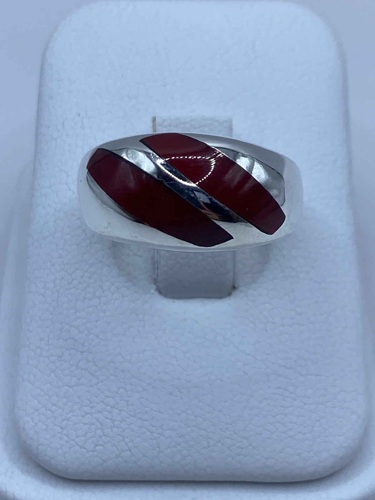 Anillo de plata con dos incrustaciones de coral rojo en la mano de una persona