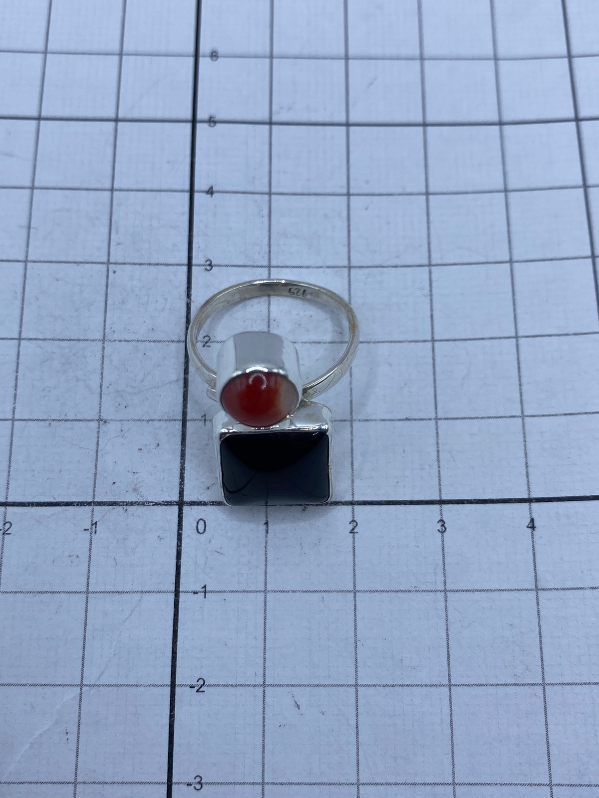 Detalle del anillo sobre regla de centímetros — aproximadamente 1.5 × 2 cm de frente