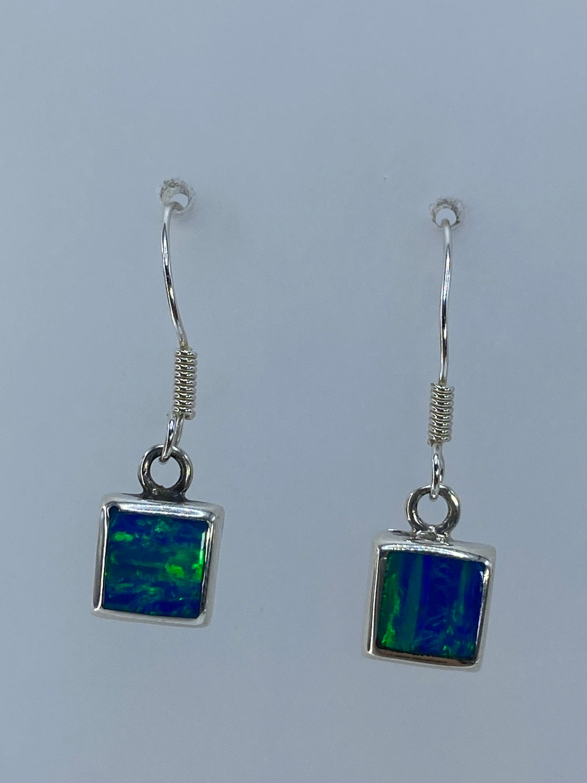 Aretes cuadrados de plata 925 mostrando el juego de colores del ópalo de fuego