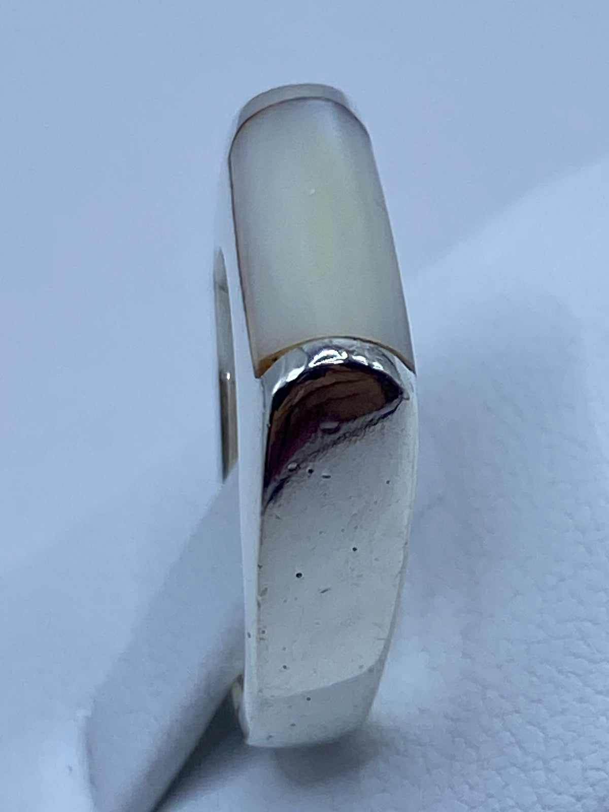 Anillo puesto en dedo, luciendo la perla con luster nacarado