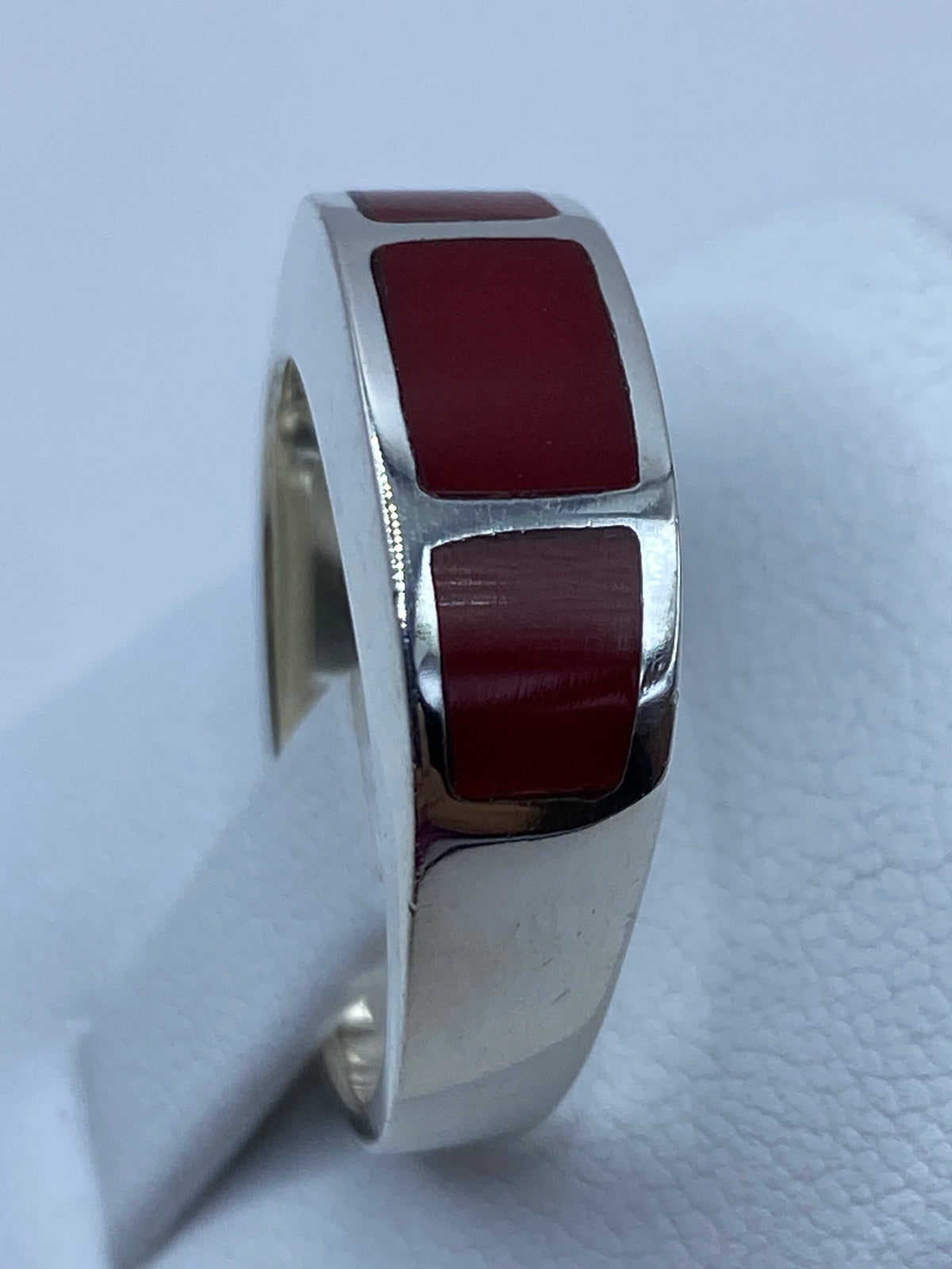 Anillo puesto en dedo mostrando el coral rojo brillante y la plata pulida