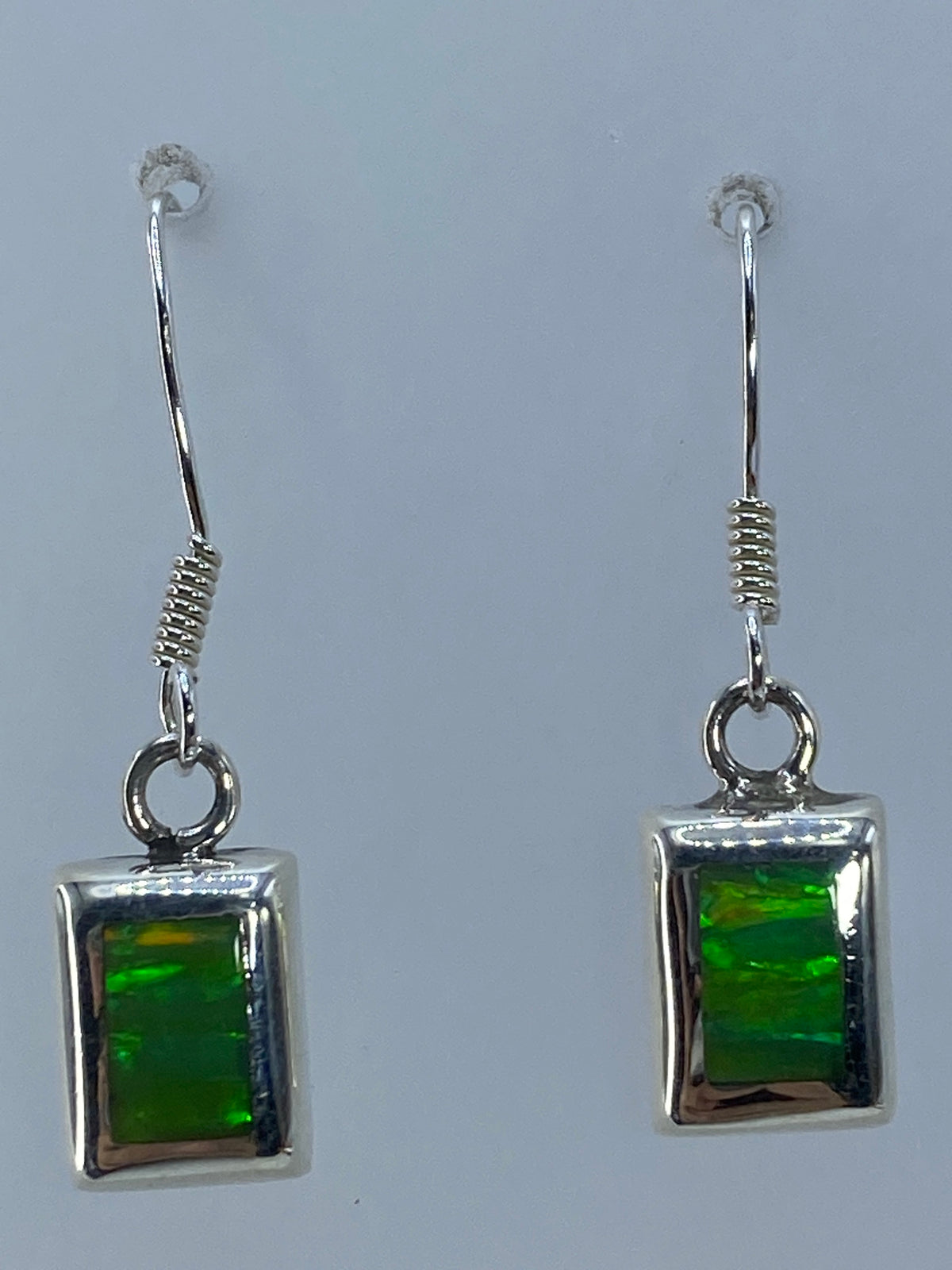 Los dos aretes de plata 925 y ópalo mostrando simetría y el juego de luz de la piedra