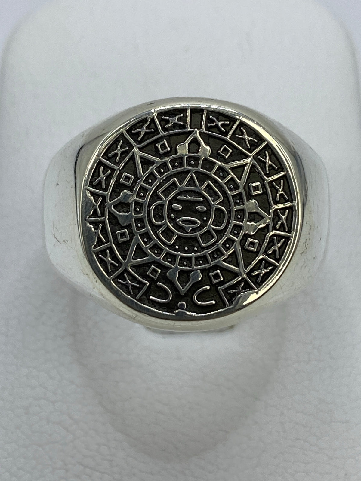 Anillo de plata repujado con Calendario Azteca en la mano, mostrando el relieve del sol central