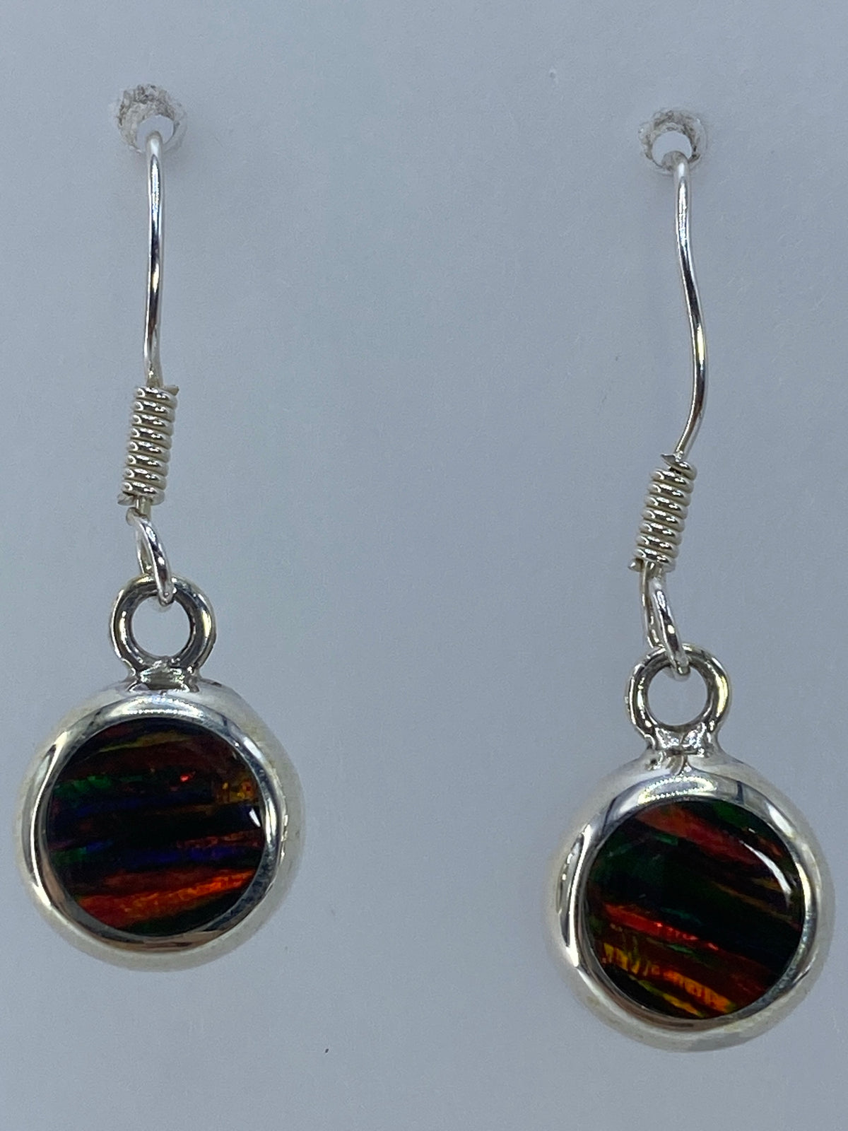 Aretes de 3 cm de largo colgando, mostrando el juego de colores del ópalo