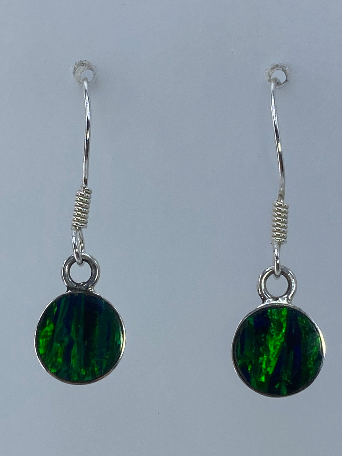 Par de aretes de plata con ópalo de fuego verde sobre fondo blanco