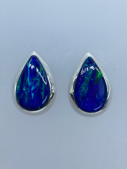 Par de aretes de plata con ópalo de fuego azul de gota, mostrando el brillo profundo de la piedra