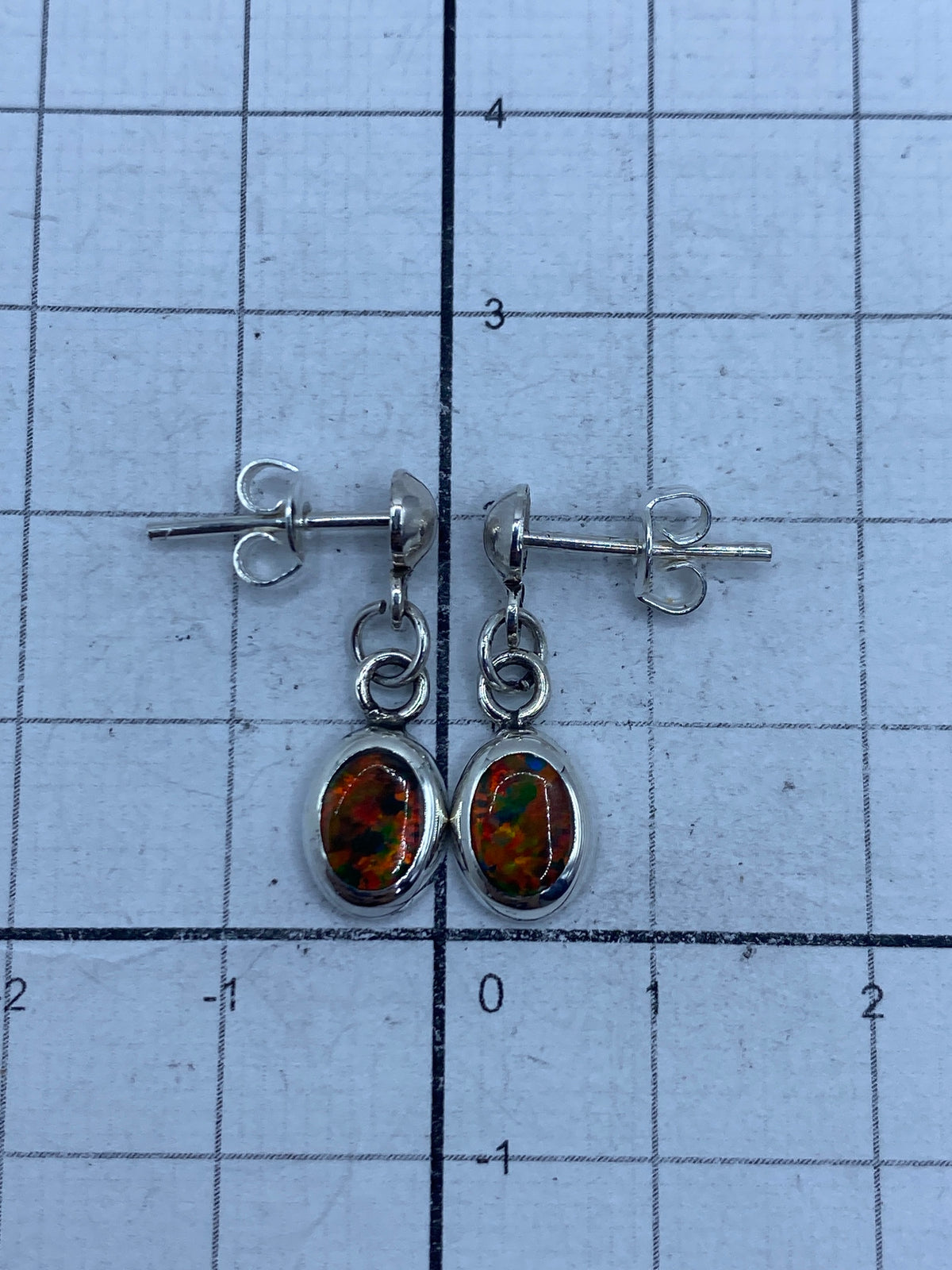 Aretes de ópalo sobre fondo blanco, vista frontal del par