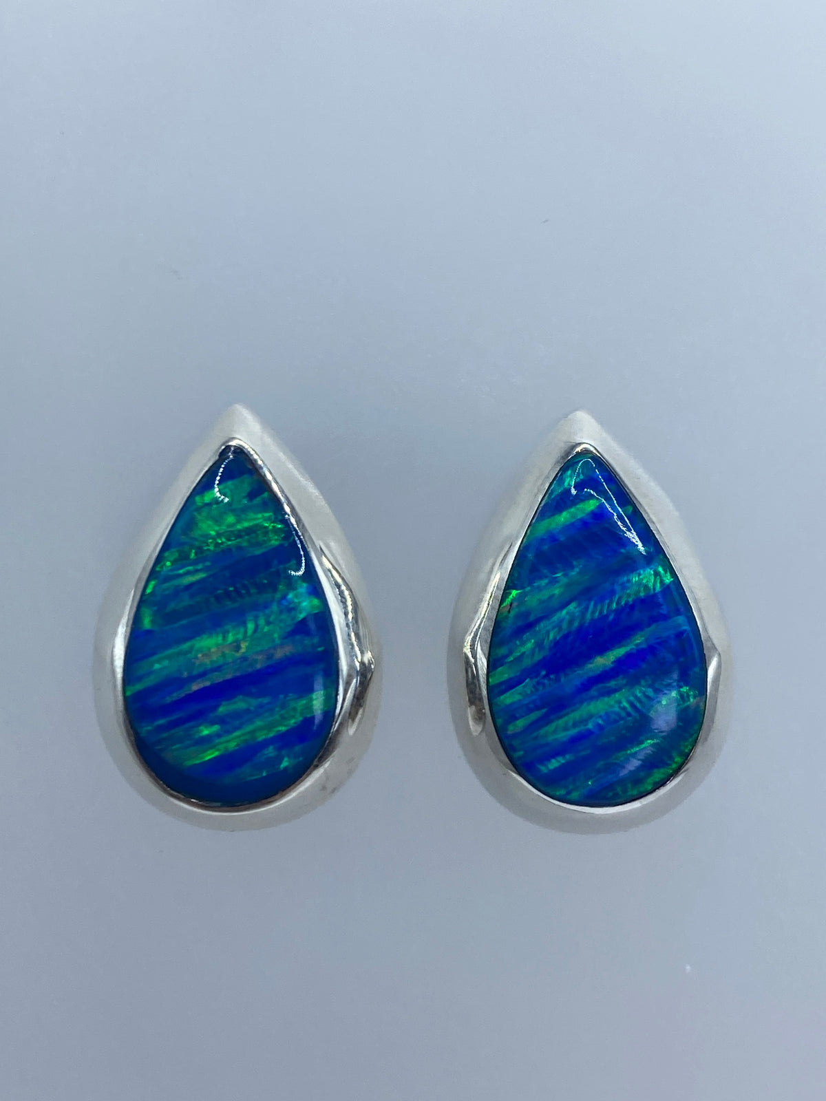 Par de aretes de plata en gota con ópalo de fuego azul engastado a mano