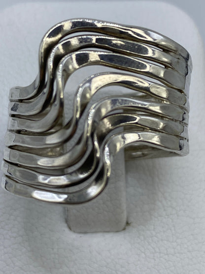Anillo de plata repujado con ondas asimétricas en la mano de una mujer