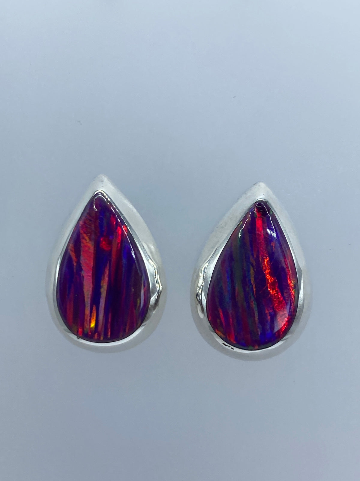 Par de aretes de plata 925 con ópalo de fuego morado, mostrando destellos anaranjados