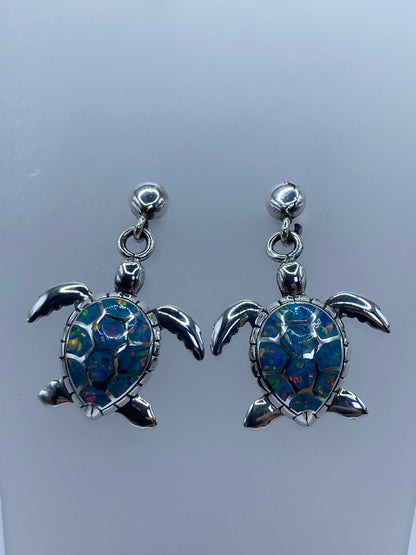 Arete individual de tortuga marina con ópalo multicolor mostrando el engaste a mano