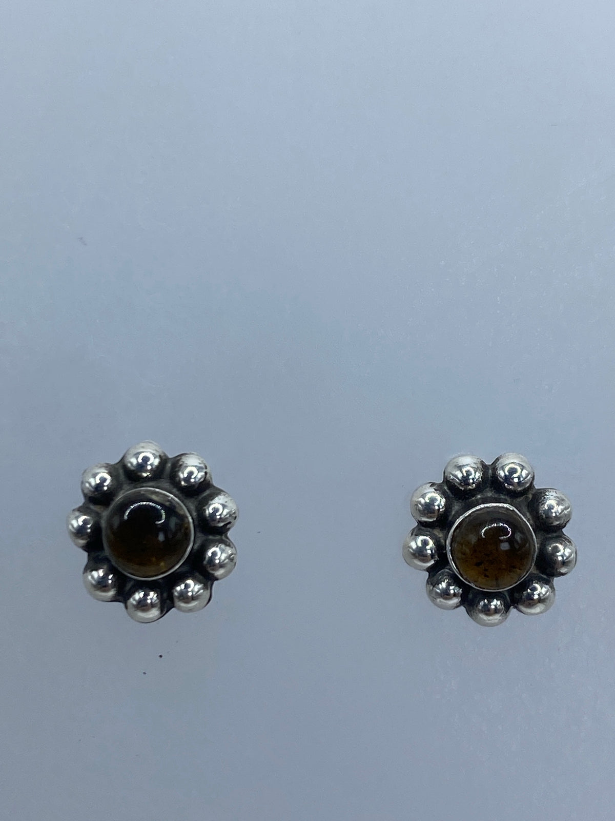 Par de aretes sobre regla de centímetros mostrando tamaño de 0.9 cm