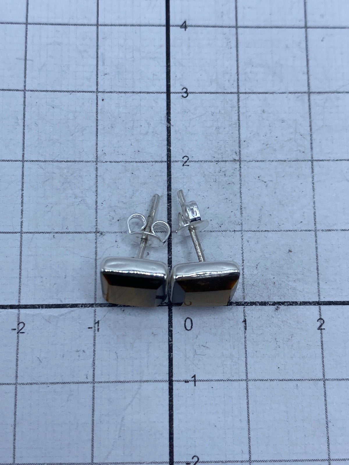 Aretes sobre papel milimetrado mostrando el tamaño: 0.8 cm × 9 mm