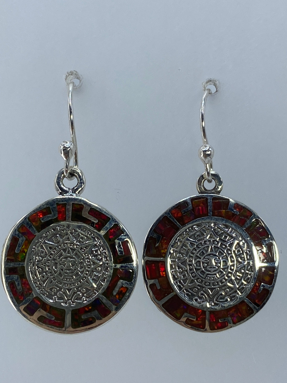 Aretes de ópalo de fuego multicolor colgando, mostrando el brillo de la piedra