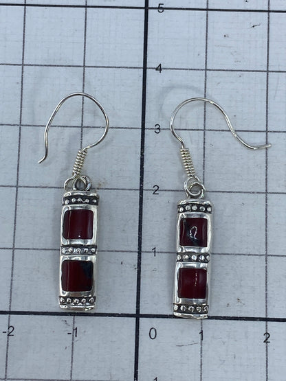 Aretes de plata con coral rojo puesto en la oreja, vista de cómo se ven en uso