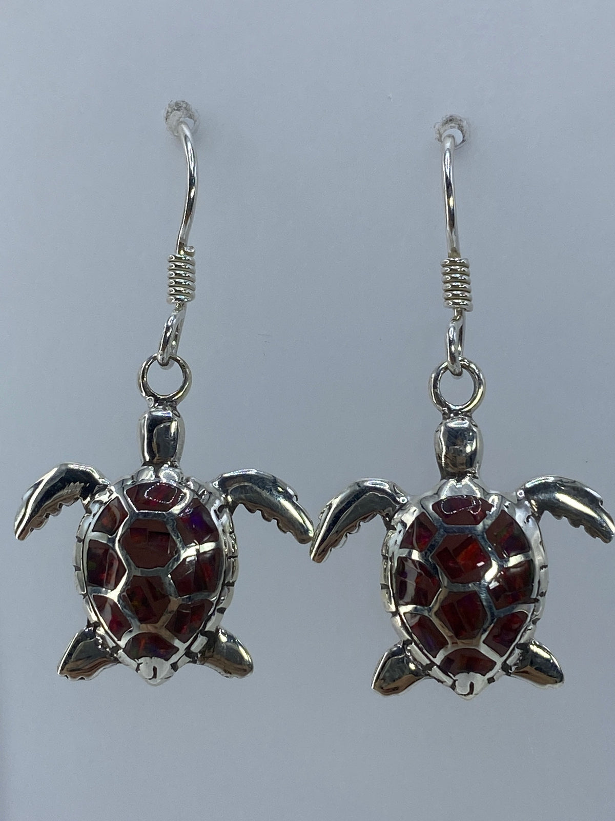 Aretes largos de plata con ópalo de fuego multicolor, colgando en posición frontal