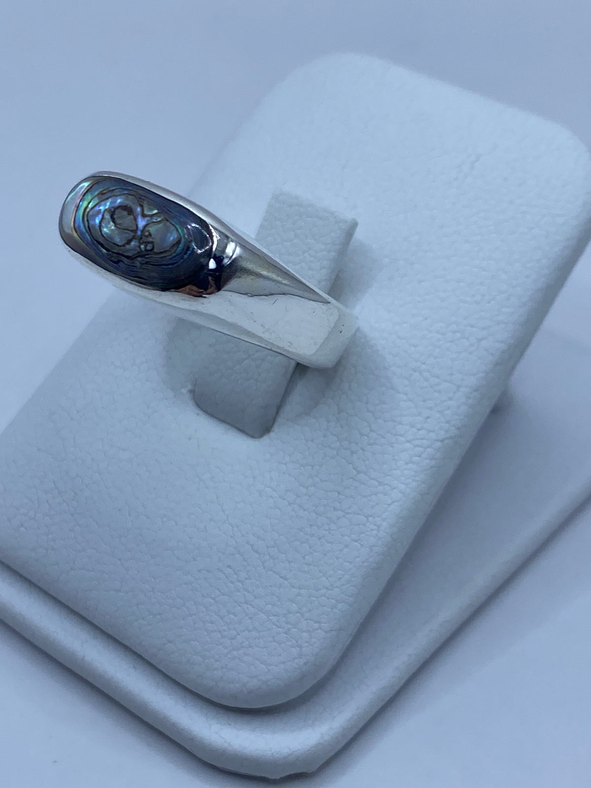 Anillo de plata engastado a mano con concha de abulón en perfil, mostrando el relieve del engaste