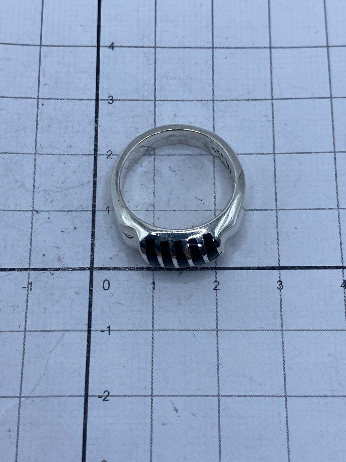 Vista lateral del anillo de plata con ónix sobre regla de medidas