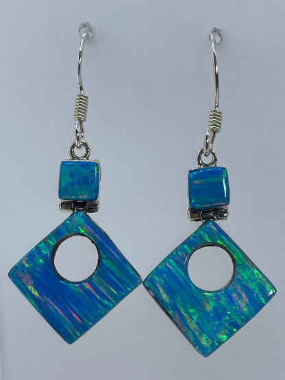 Aretes de opalo fuego en plata 950 mostrando el destello verde del opalo