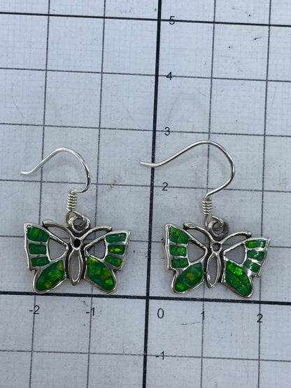 Aretes de mariposa ópalo verde sobre fondo blanco mostrando el Quinto 950