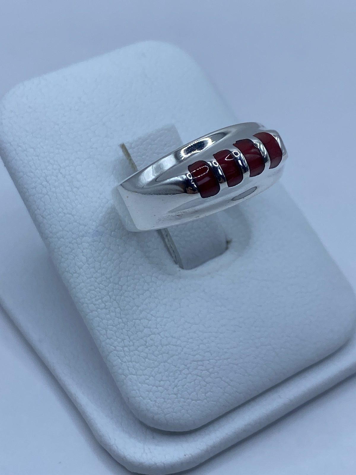 Anillo de plata con coral rojo colocado en dedo, mostrando el color intenso