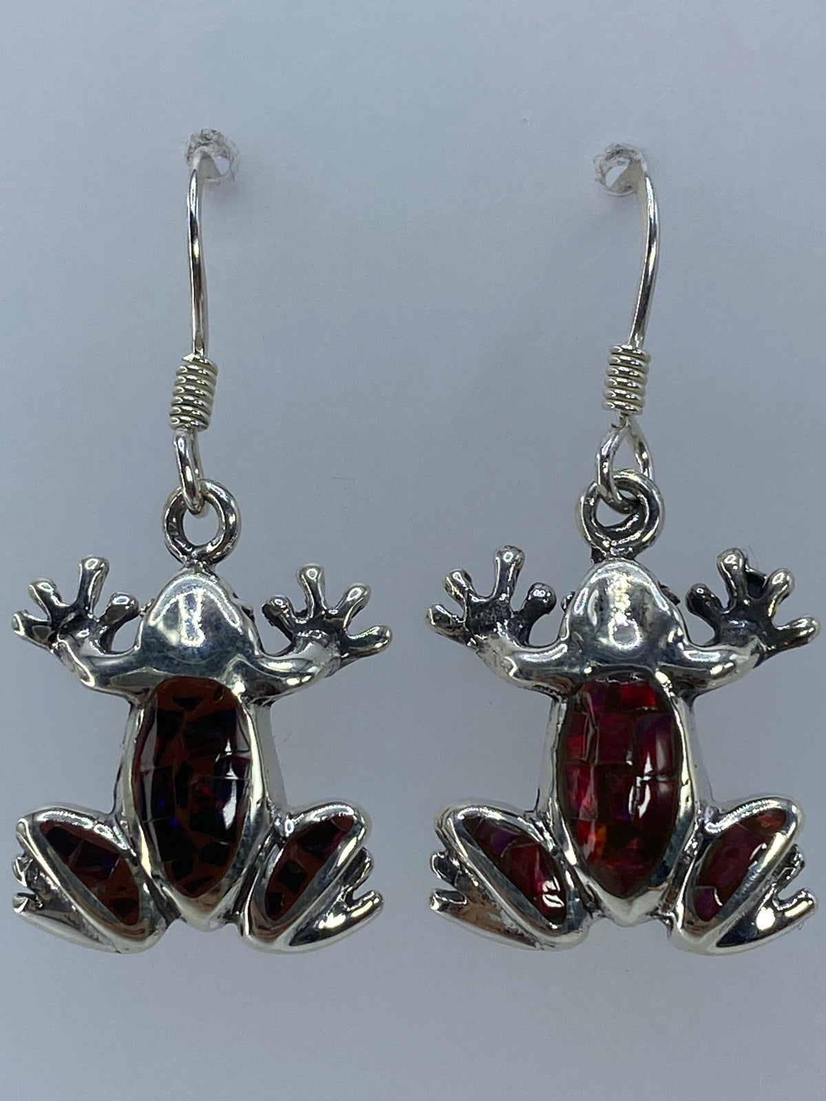 Aretes de rana en plata 950 sobre fondo gris, mostrando los destellos del ópalo