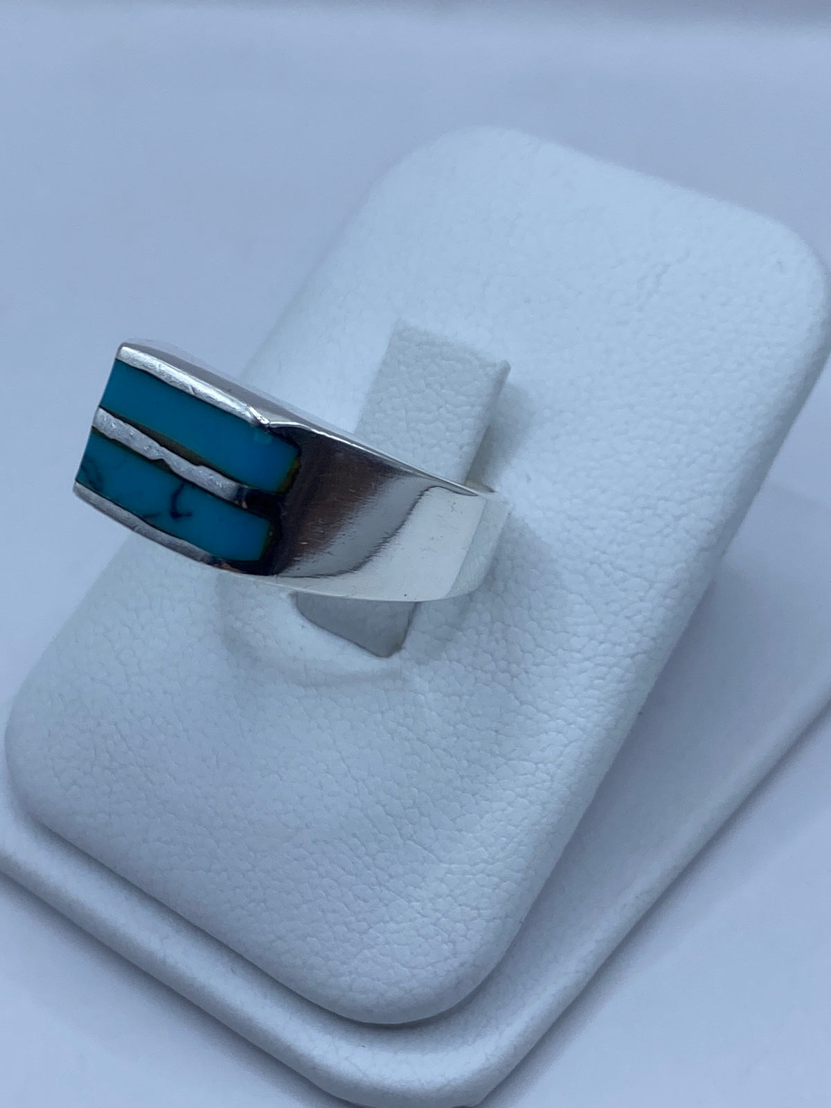 Anillo en mano mostrando la turquesa azul y el pulido plateado en uso