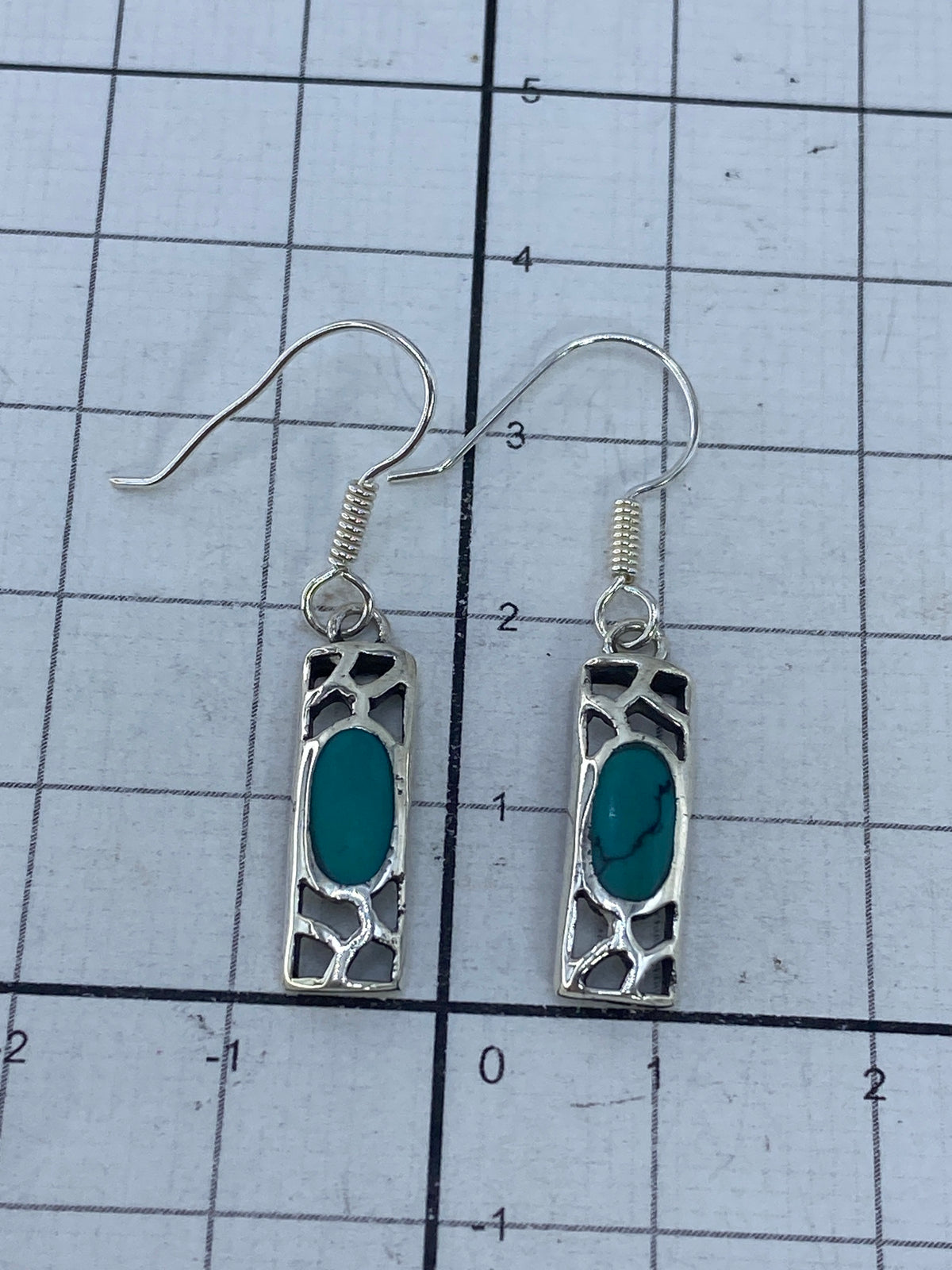 Aretes sobre regla de medición mostrando 3.7 cm de largo