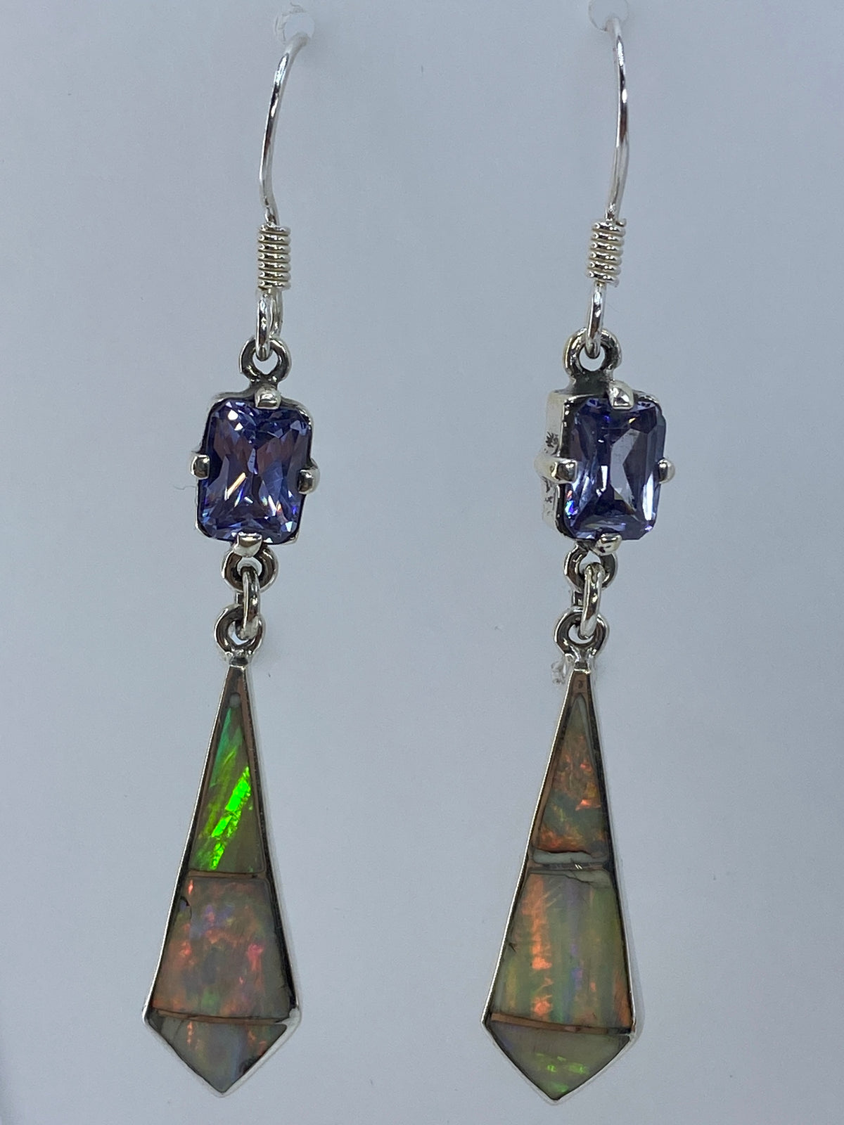 Vista de perfil de los aretes con el ópalo de fuego refractando luz en verdes y naranjas