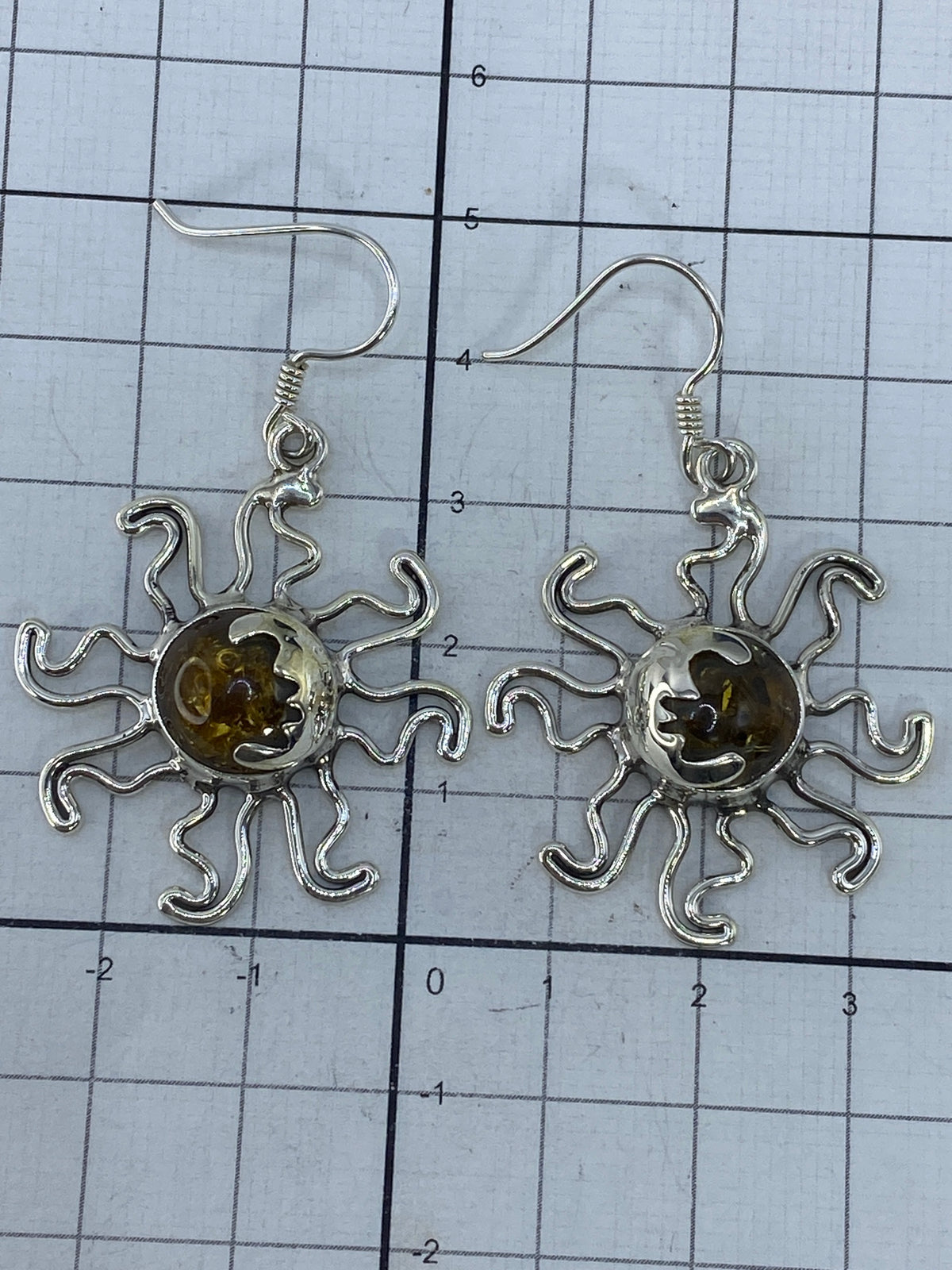 Aretes de sol sobre fondo blanco mostrando el Quinto 925 grabado
