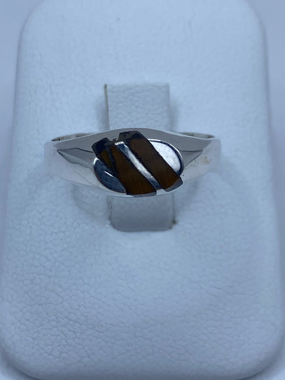 Anillo de plata 925 con piedra cafe engastada, visto de frente sobre anillo blanco