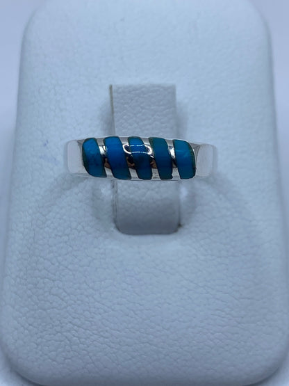 Anillo de plata con cinco segmentos de turquesa azul en la mano