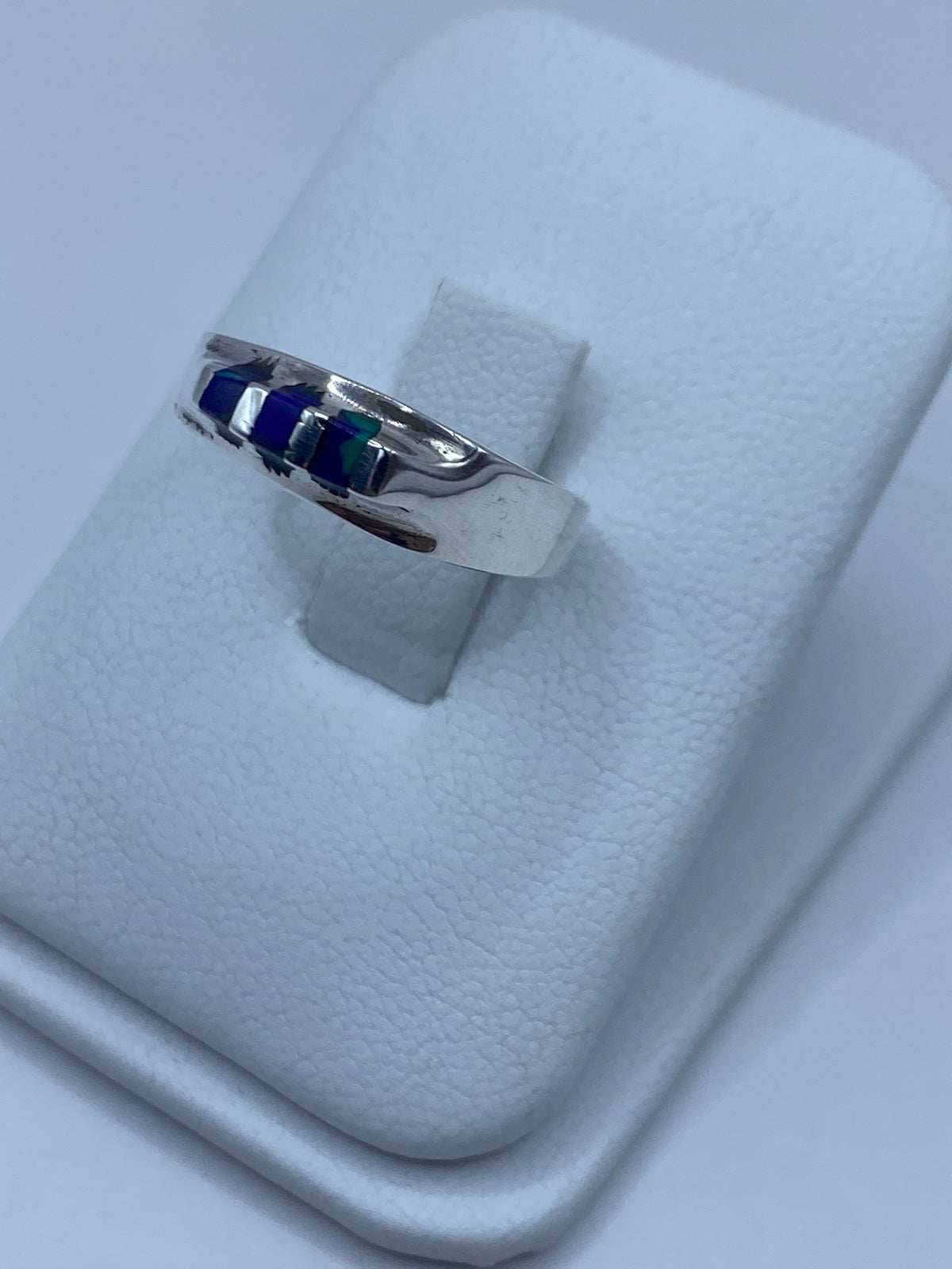 Anillo de plata con piedra azul puesto en el dedo, mostrando el engaste a mano