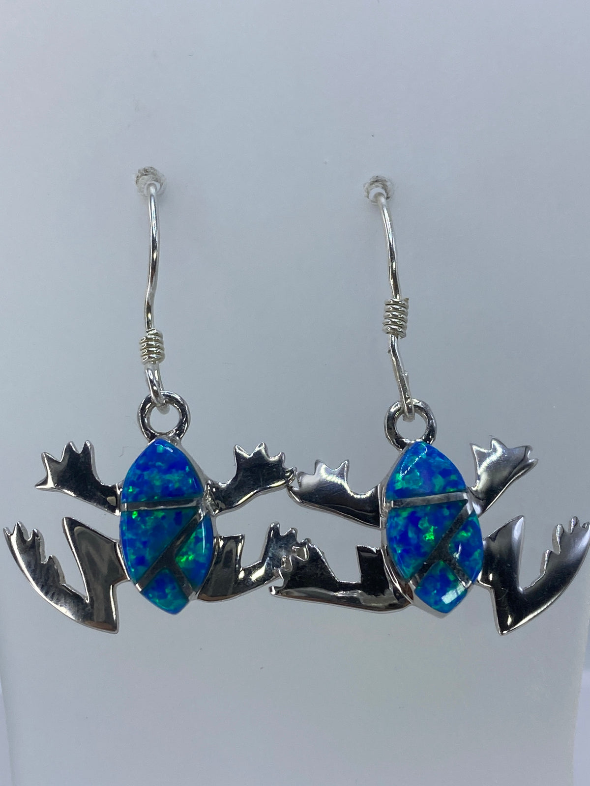 Par de aretes de plata con ópalo de fuego verde olivo sobre fondo blanco