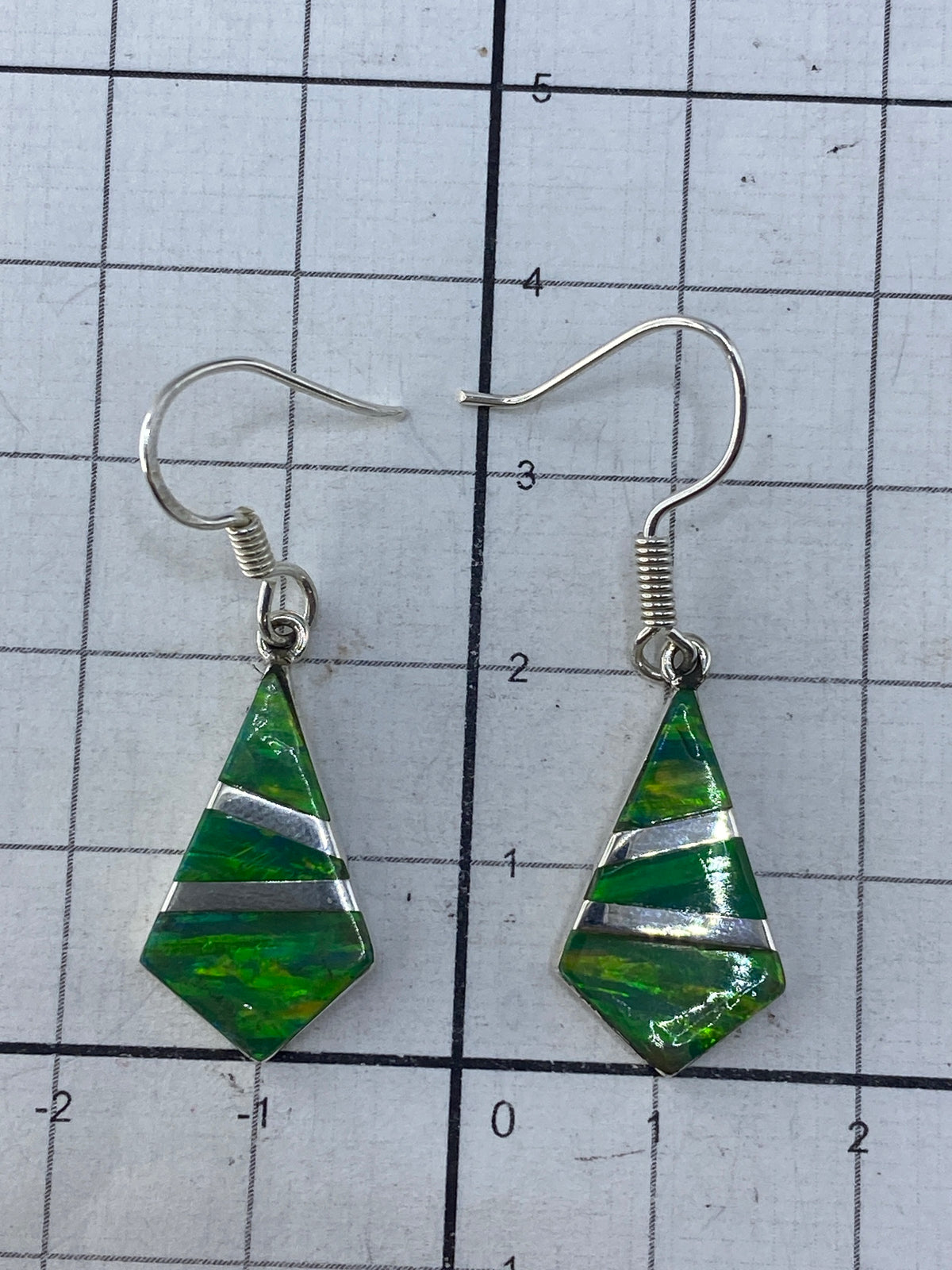 Aretes puestos en oreja, mostrando el largo de 3.5 cm y el brillo del ópalo verde limón