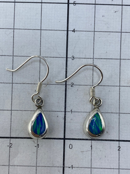 Aretes colgando mostrando el color verde olivo profundo del ópalo de fuego
