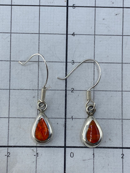 Aretes sobre fondo gris neutro con brillo del ópalo y Quinto 925 visibles