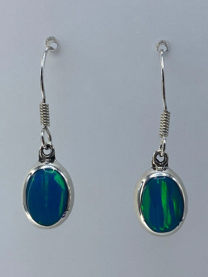 Detalle de los aretes mostrando el ópalo de fuego con sus tonos verdes y azulados engastado en plata