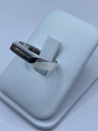 Anillo en la mano mostrando los destellos verdes y azules del abulón