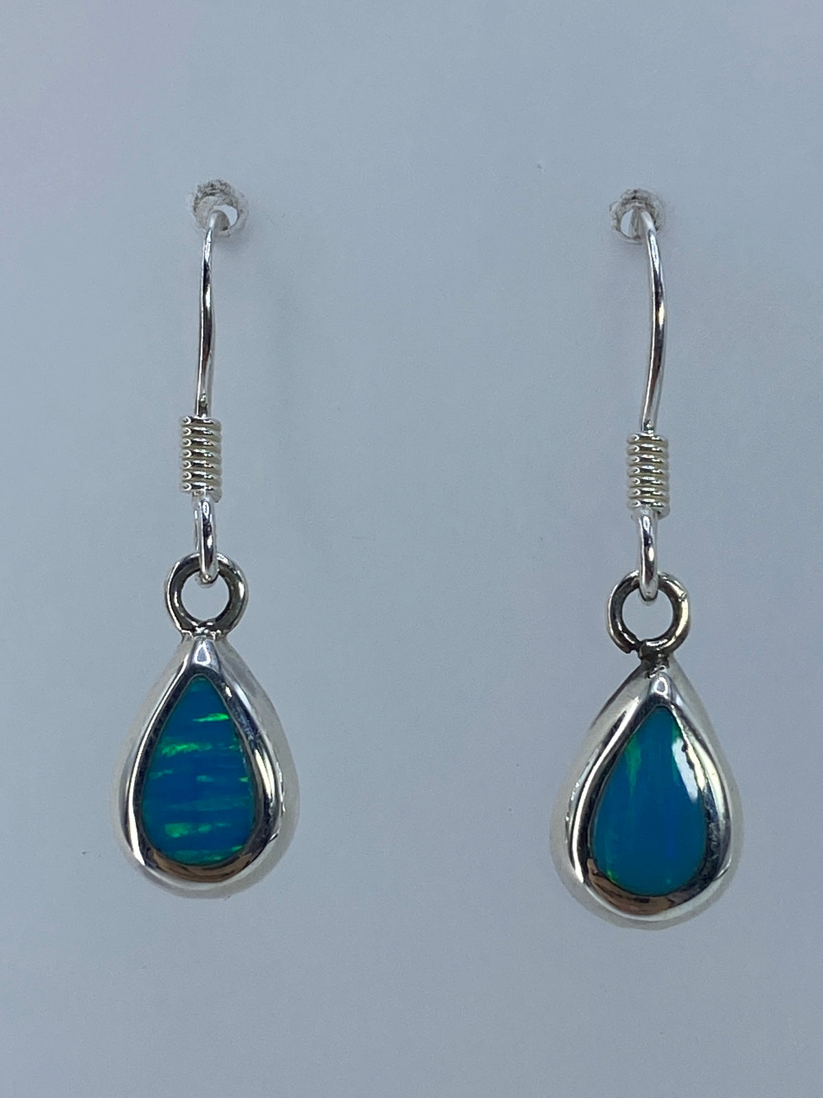 Detalle de los aretes mostrando el color verde olivo y los destellos del ópalo