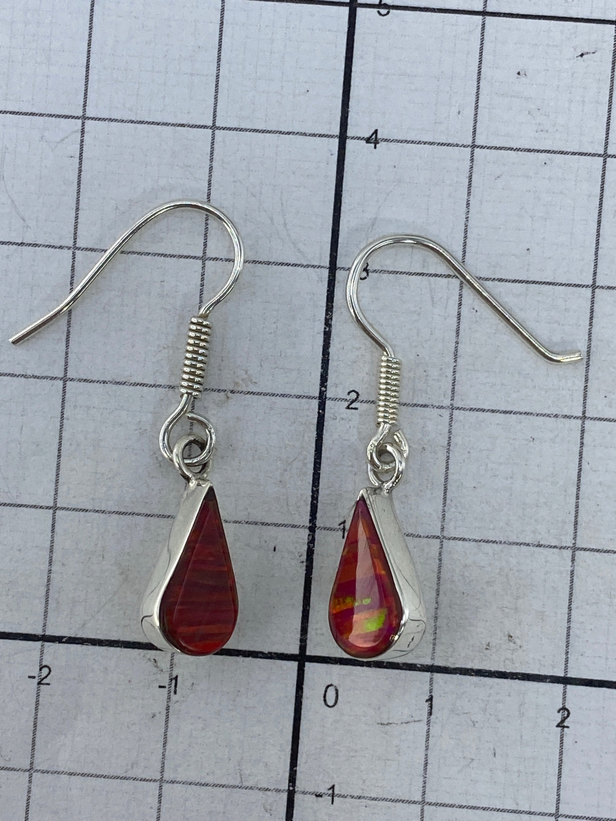 Aretes sobre regla de medición confirmando largo de 3.3 cm
